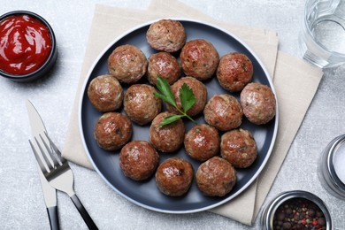Photo of Tasty cooked meatballs with parsley served on light grey table, flat lay