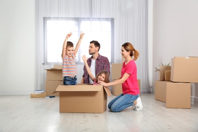 Photo of Happy family playing with cardboard box in their new house. Moving day