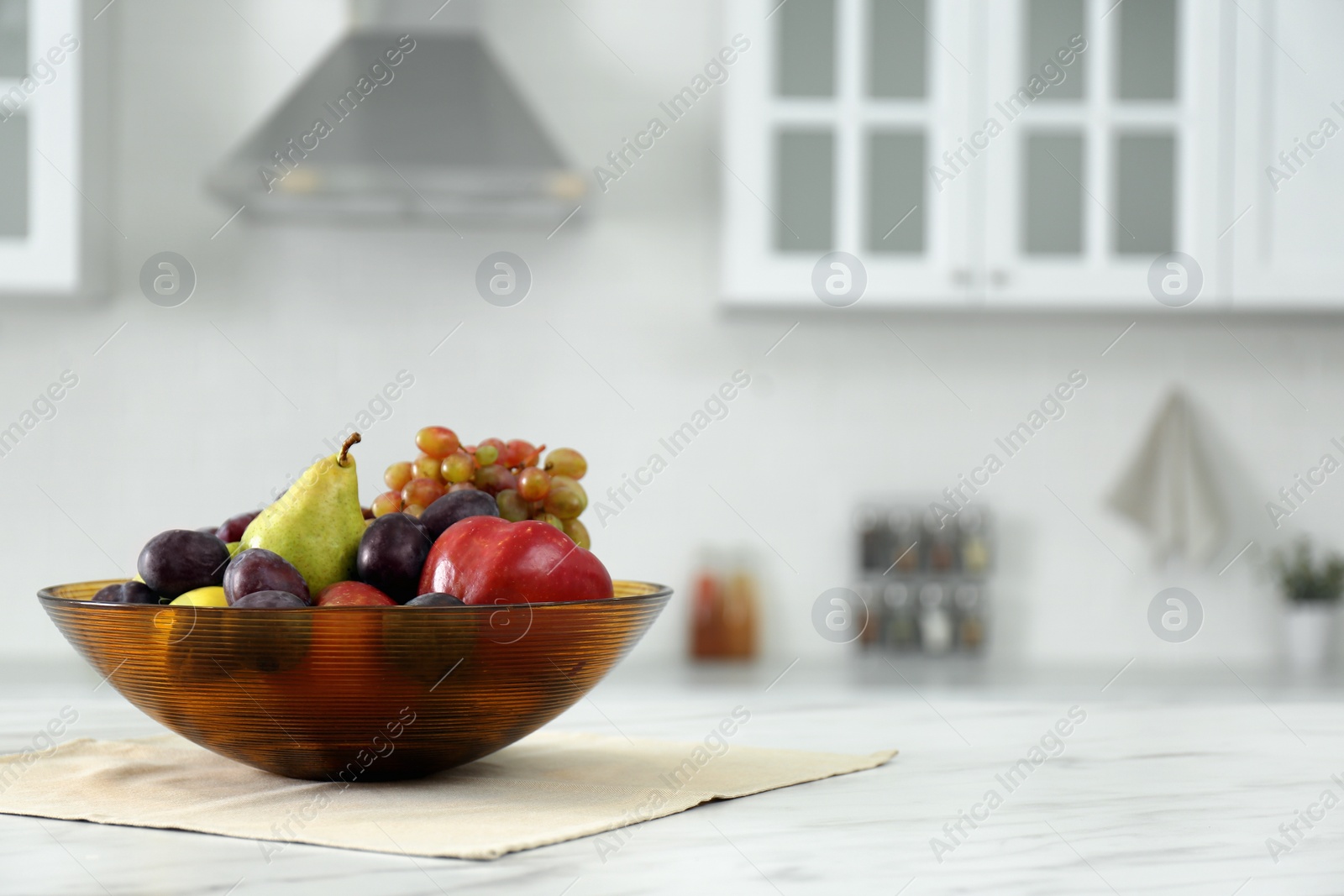 Photo of Different fresh fruits in bowl on white kitchen table. Space for text