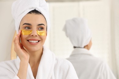 Photo of Beautiful young woman with under eye patches at home, space for text