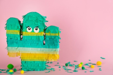 Photo of Cactus shaped pinata on pink background. Space for text