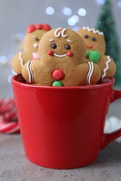 Photo of Gingerbread men in cup on light table against blurred lights, closeup