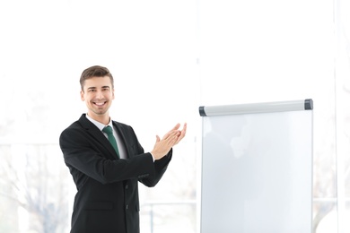 Photo of Business trainer applauding near flip chart board indoors