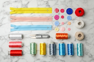 Photo of Flat lay composition with color sewing threads on marble background