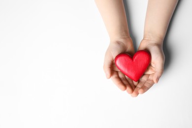 Photo of Woman holding red heart in hands on white background, top view