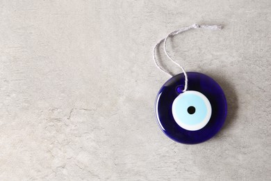 Photo of Evil eye amulet on light grey table, top view. Space for text