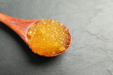 Photo of Fresh pike caviar in spoon on black table, closeup