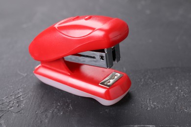 Photo of One red stapler on black textured table