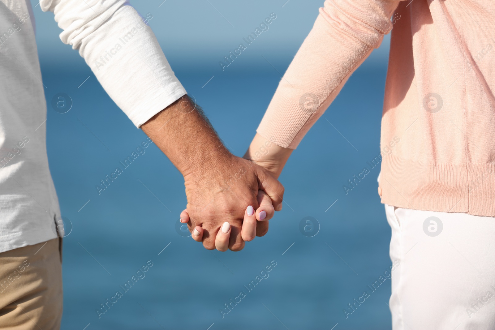 Photo of Happy couple holding hands at beach, closeup