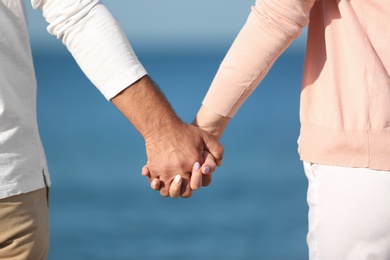 Happy couple holding hands at beach, closeup