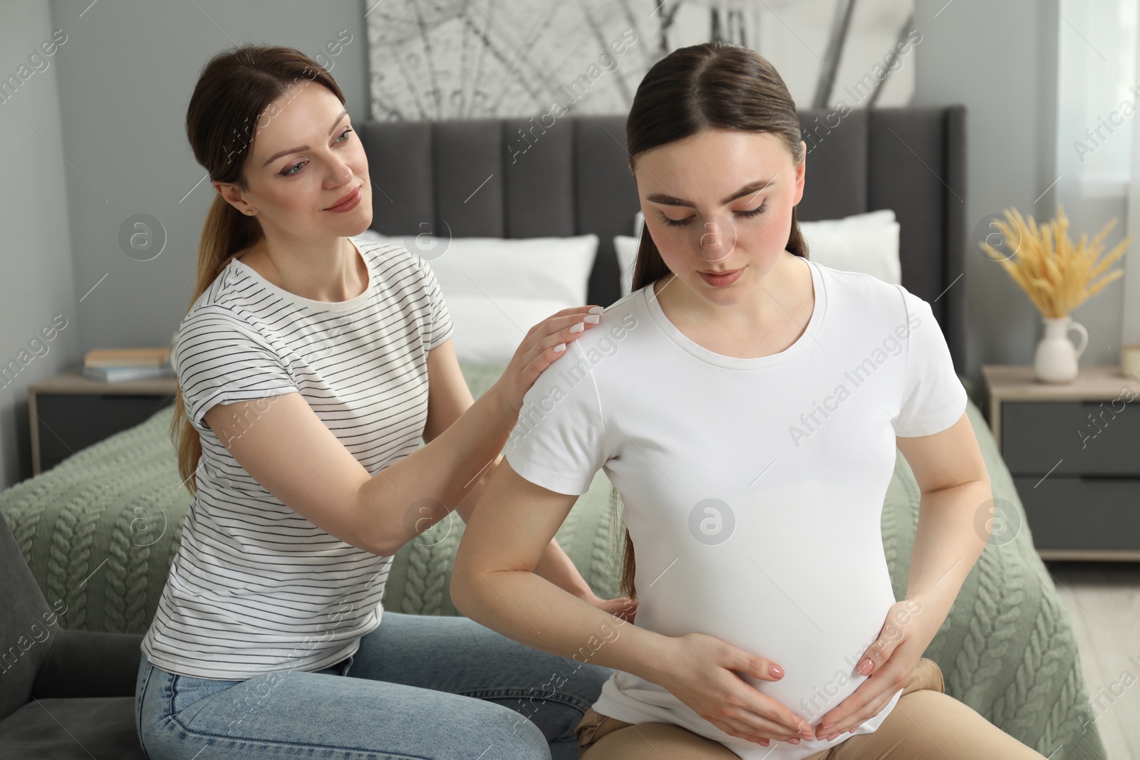 Photo of Doula taking care of pregnant woman in bedroom. Preparation for child birth