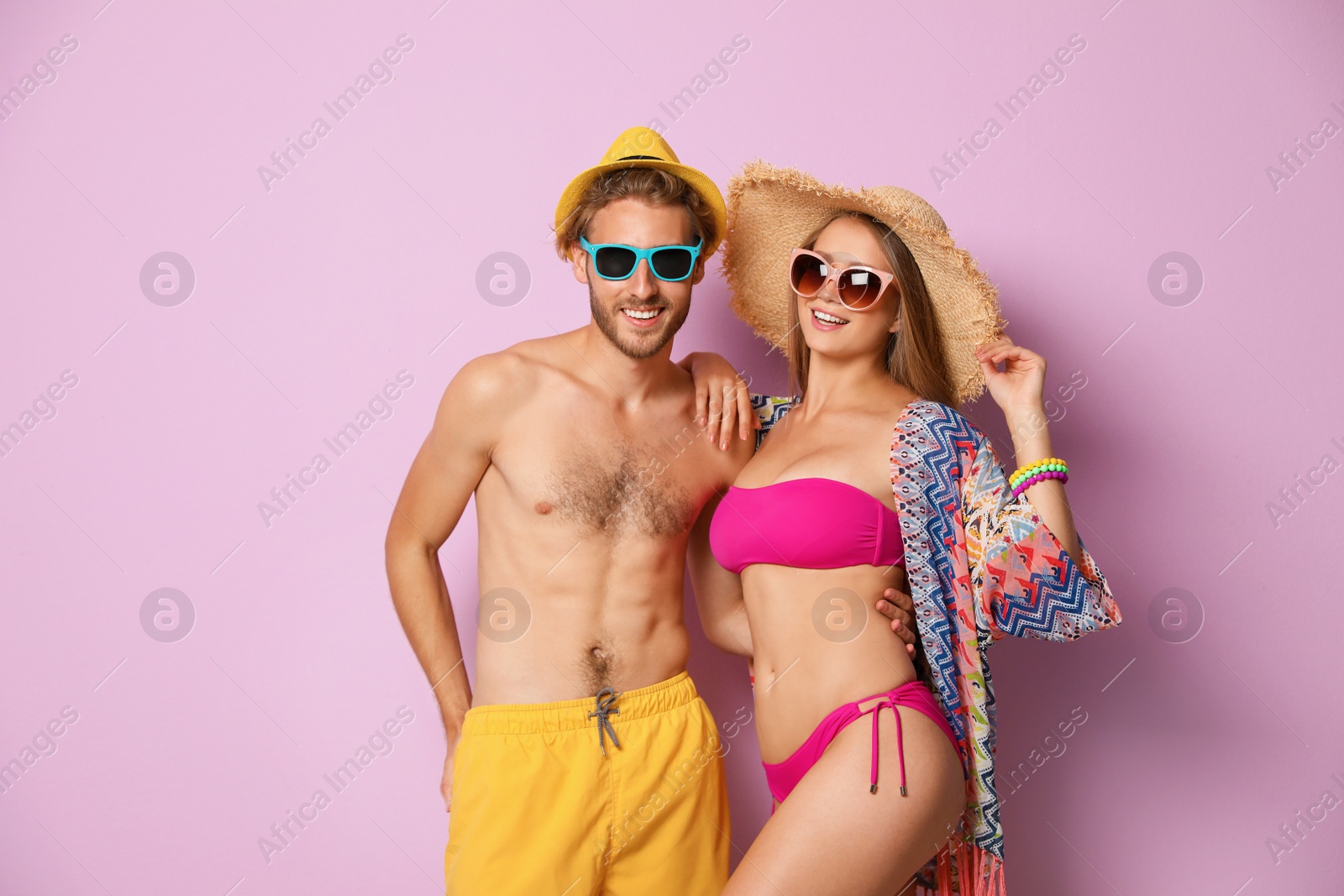 Photo of Happy young couple in beachwear on color background