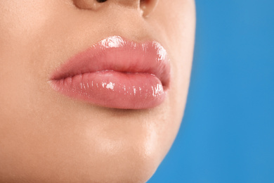 Photo of Young woman with beautiful full lips on light blue background, closeup