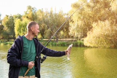 Photo of Man with rod fishing at riverside on sunny day. Recreational activity