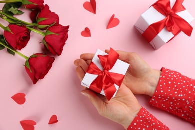 Photo of Woman holding gift box on pink background, top view. Valentine's Day celebration