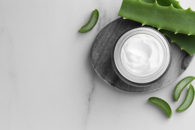 Photo of Jar with cream and cut aloe leaves on white marble table, flat lay. Space for text