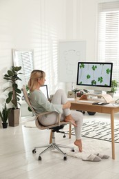 Photo of Woman with cup of tea at table in light room. Home office