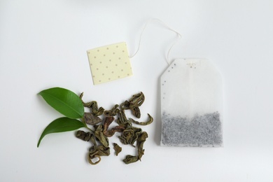Photo of Tea bag and dried leaves on white background, top view