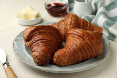 Photo of Plate with tasty croissants on light table, closeup