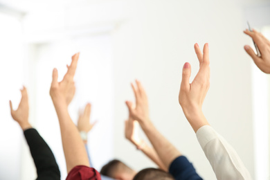 Photo of People raising hands to ask questions at business training indoors, closeup