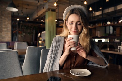 Photo of Young woman with cup of coffee at cafe in morning