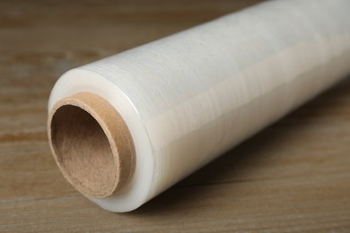 Photo of Roll of plastic stretch wrap film on wooden table, closeup