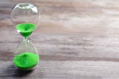 Photo of Hourglass with flowing sand on table. Time management
