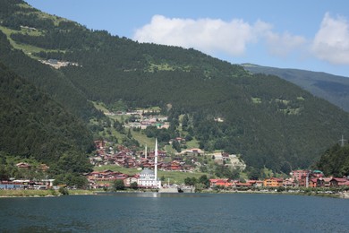 Photo of Buildings under mountains near lake on sunny day
