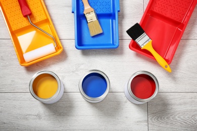 Photo of Flat lay composition with cans of paint and decorator tools on wooden background