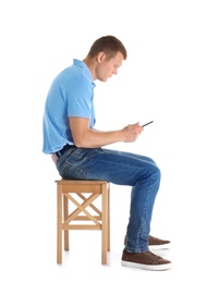 Photo of Man with mobile phone sitting on stool against white background. Posture concept