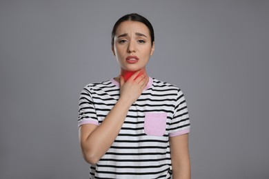 Image of Young woman suffering from sore throat on grey background. Cold symptoms