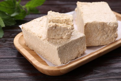 Photo of Pieces of tasty halva on wooden table, closeup
