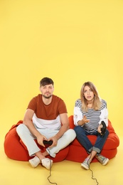 Photo of Emotional couple playing video games with controllers on color background. Space for text