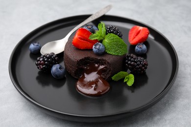 Photo of Plate with delicious chocolate fondant, berries and mint on grey table, closeup
