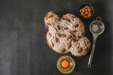 Delicious Italian Easter dove cake (traditional Colomba di Pasqua) and ingredients on black table, top view. Space for text