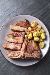 Photo of Delicious fried beef meat, vegetables and thyme on black table, top view