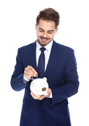 Photo of Young businessman putting money into piggy bank on white background