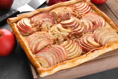 Photo of Tasty apple pie with nuts and fresh fruits on grey table, closeup