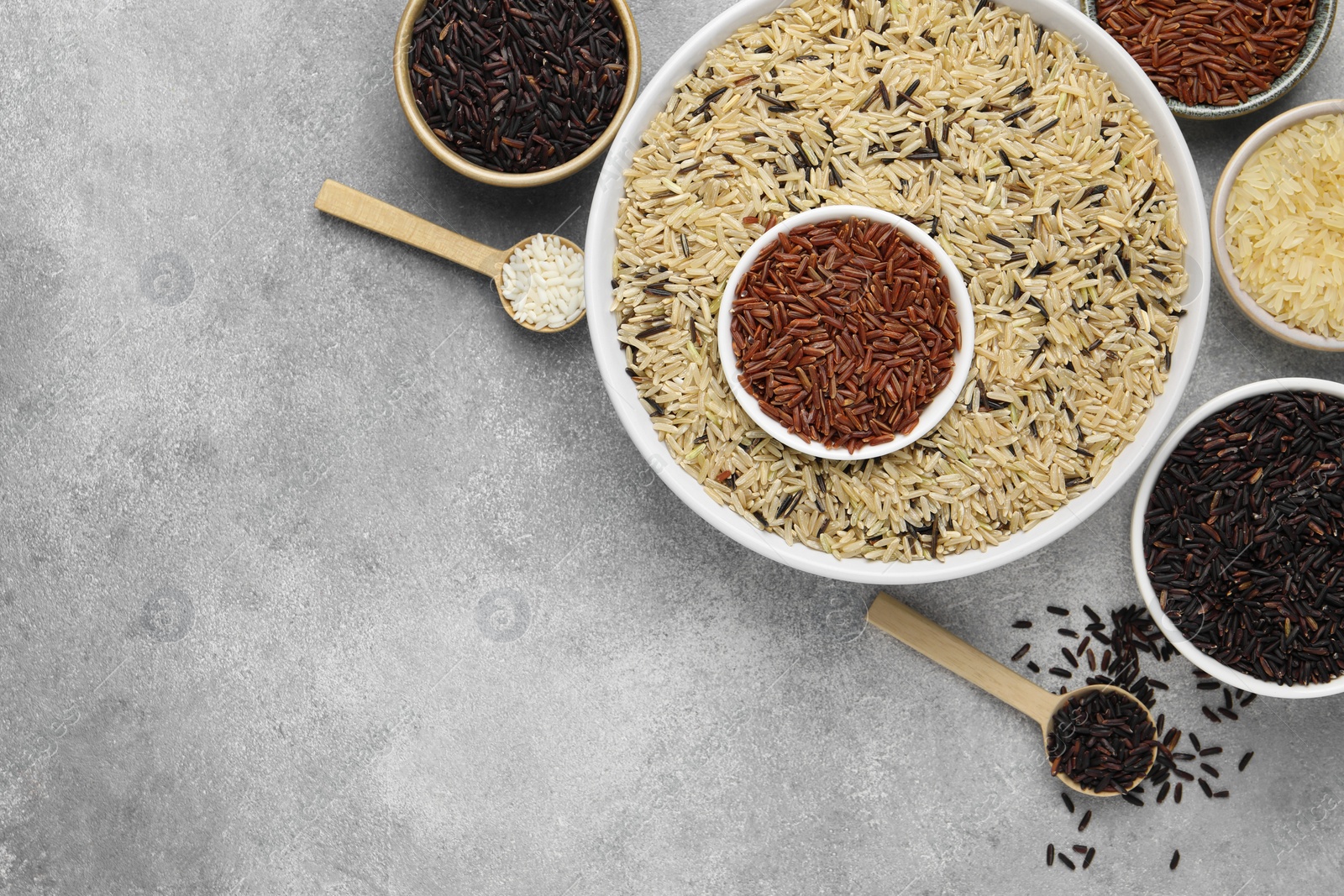 Photo of Different sorts of rice on grey table, flat lay. Space for text