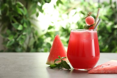 Photo of Delicious fresh watermelon drink on grey table. Space for text