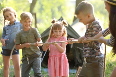 Photo of Little children pulling rope outdoors. Summer camp