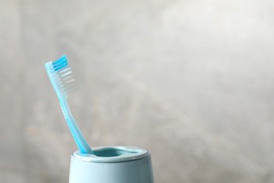 Photo of Plastic toothbrush in holder on light grey background, closeup. Space for text