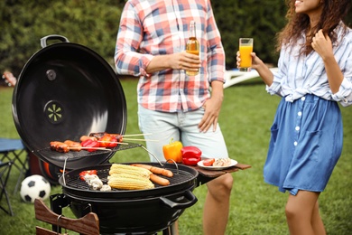 Photo of People with beverages near barbecue grill outdoors