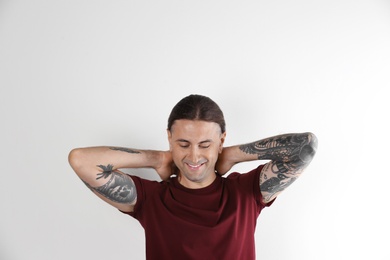 Photo of Young man with stylish tattoos on white background