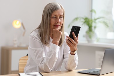 Photo of Senior woman using mobile phone at home