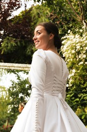 Young bride wearing beautiful wedding dress in park
