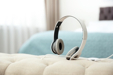 Photo of Stylish headphones on sofa indoors. Space for text