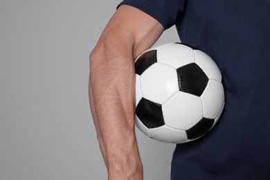 Photo of Athletic man with soccer ball on light grey background, closeup. Space for text