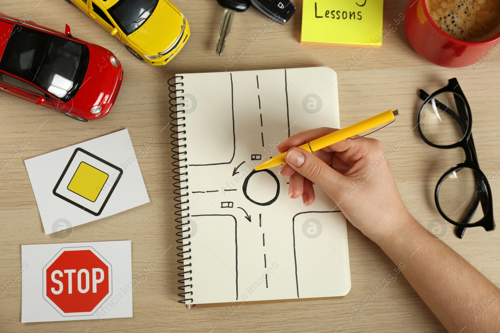 Photo of Woman with workbook for driving lessons and road signs at wooden table, top view. Passing license exam