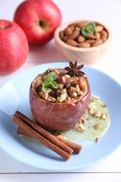 Tasty baked apple with nuts, honey, spices and mint on white wooden table